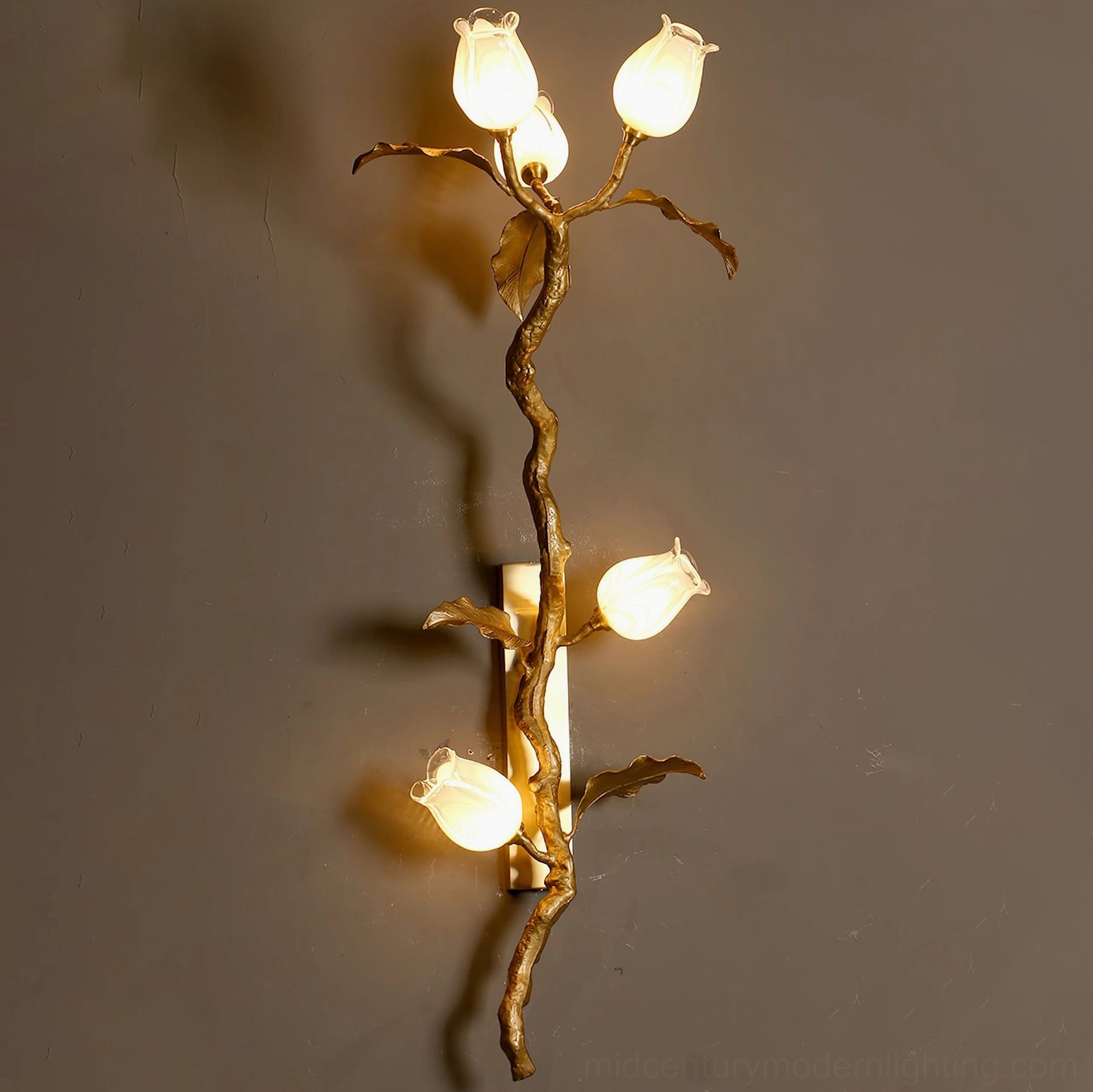 Tulip Branch Brass Wall Sconce lit overhead perspective with warm LED glow illuminating frosted glass tulips against neutral wall