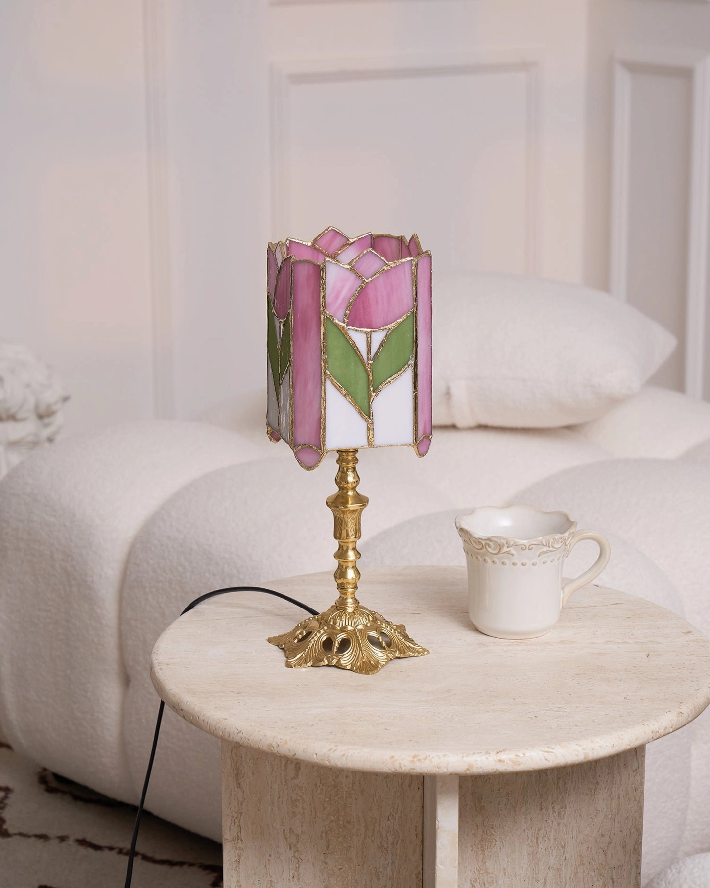 Mid-century modern tulip table lamp on bedroom nightstand with white upholstered bed and coffee mug