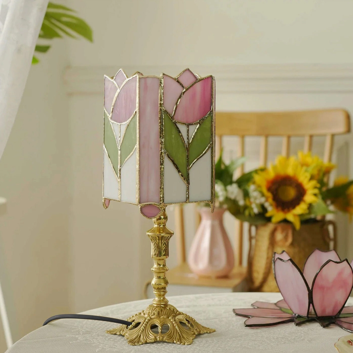 Tiffany style tulip table lamp three-quarter view beside sunflower floral arrangement and carved brass base