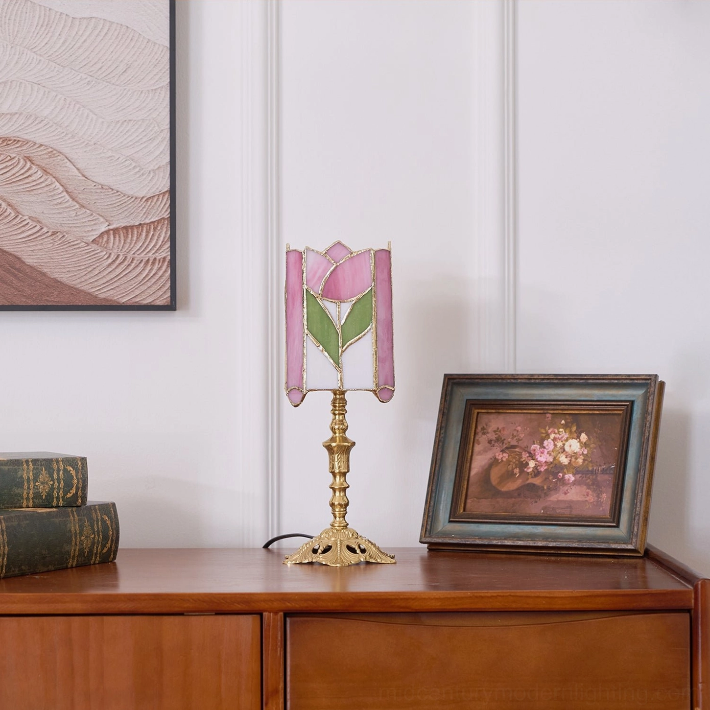 Vintage tulip desk lamp on wooden dresser with wall art, brass base, pink-green stained glass beside books