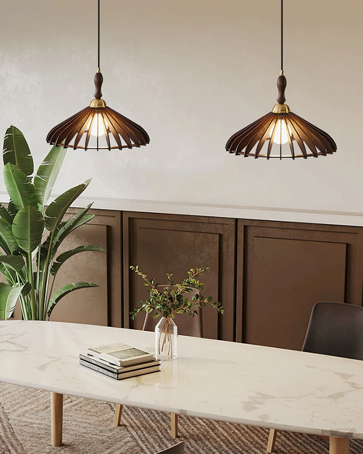 Two walnut wood umbrella pendant lamps above marble dining table with green plant and book styling