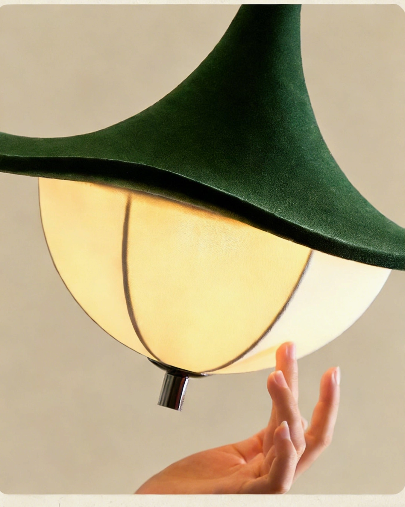 Vadar pendant light close-up showing beige segmented fabric shade and hand detail
