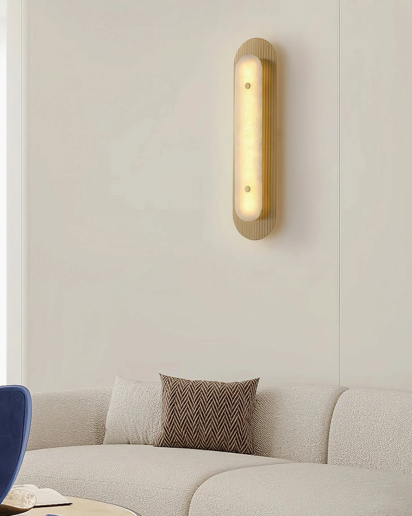 Vance Wall Sconce mounted low in living room with fabric sofa, warm modern luxury aesthetic