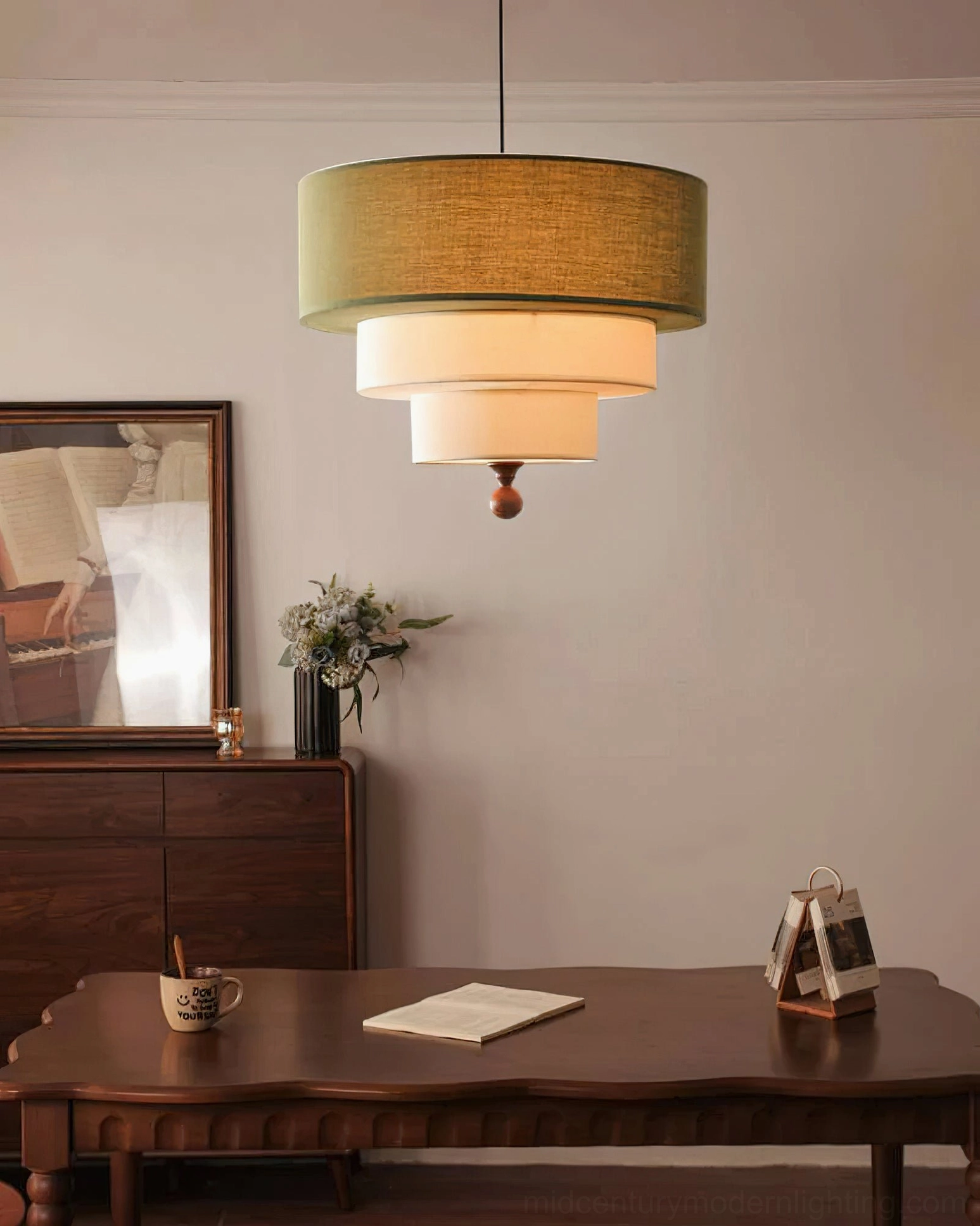 Side view of Vanelia pendant lamp with olive green top shade and cream fabric tiers, wooden finial detail visible in vintage lounge with wooden furniture