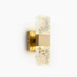 Vega gold wall sconce with textured clear glass diffuser, frontal studio view showcasing mid-century modern design