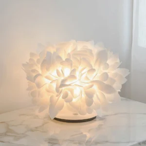 Illuminated Veli Foliage table lamp on marble bedside surface casting warm ambient light