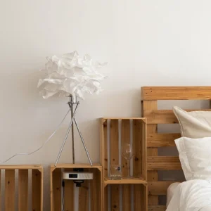 Veli paper table lamp in minimalist bedroom corner with wooden crate storage, warm ambient lighting creating soft diffused glow