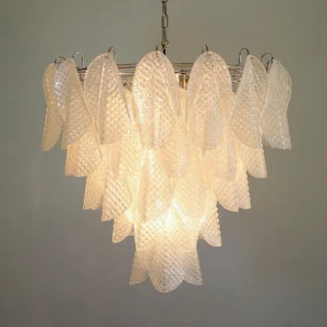 Close-up detail of ripple glass chandelier with warm glowing light illuminating textured glass petals