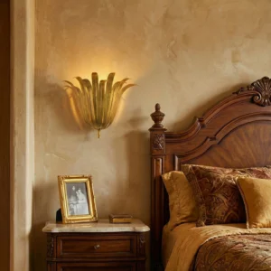 Art Deco leaf wall sconce gold finish installed above wooden carved headboard in luxury bedroom setting
