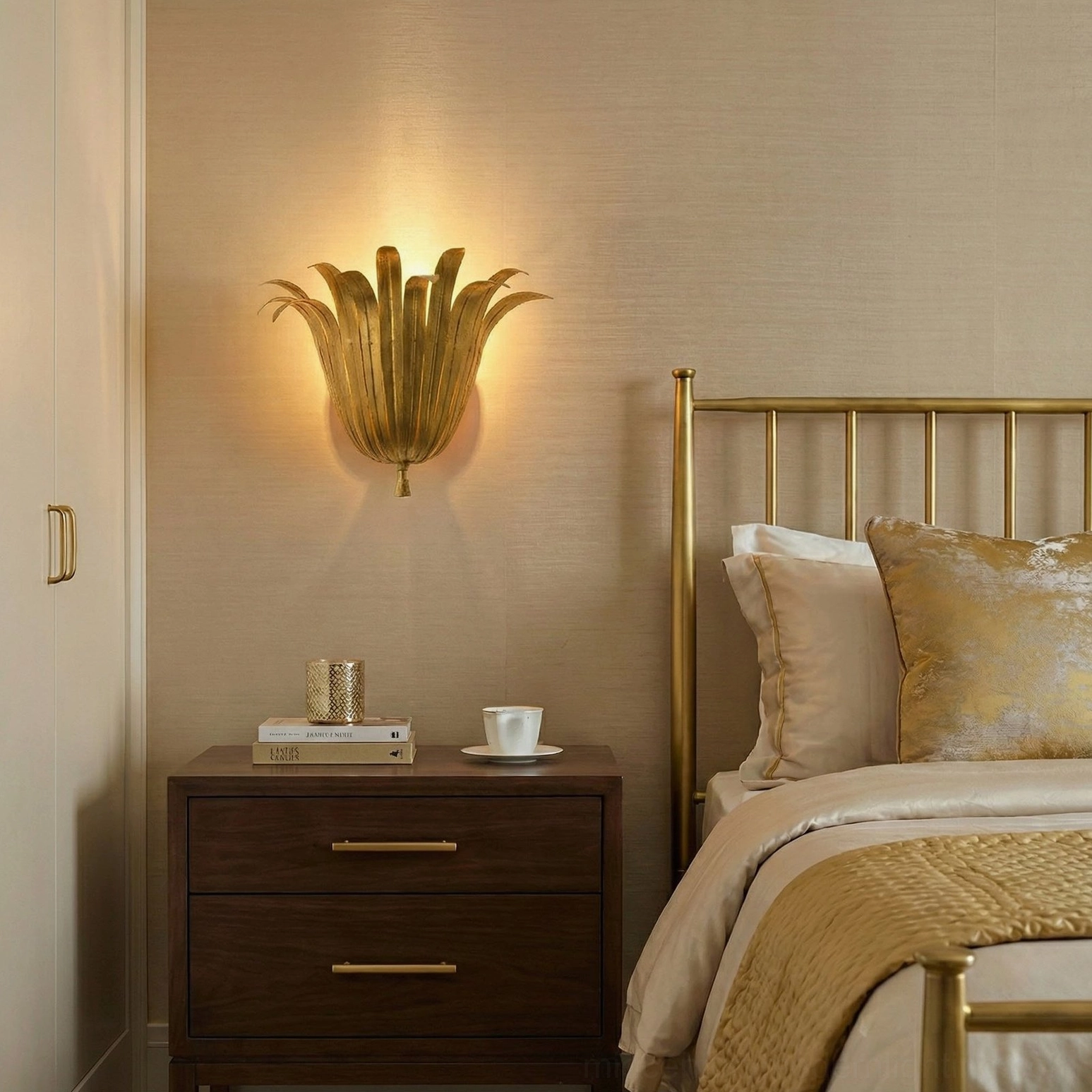 Gold botanical leaf sconce mounted on bedroom wall beside brass metal bedside cabinet with warm neutral decor