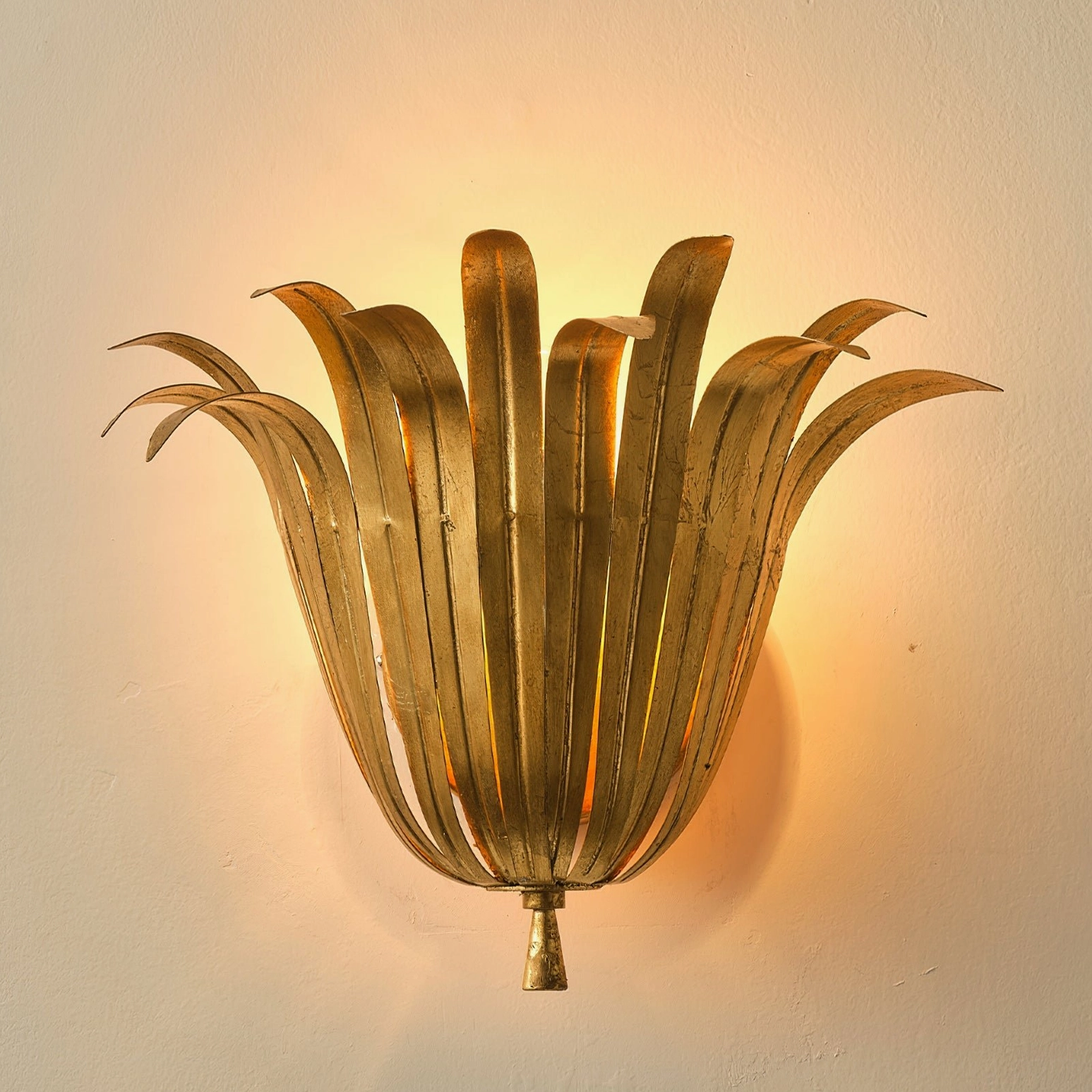 Vicenzio gold leaf wall sconce close-up with warm ambient lighting showing layered metallic leaf structure and glow effect