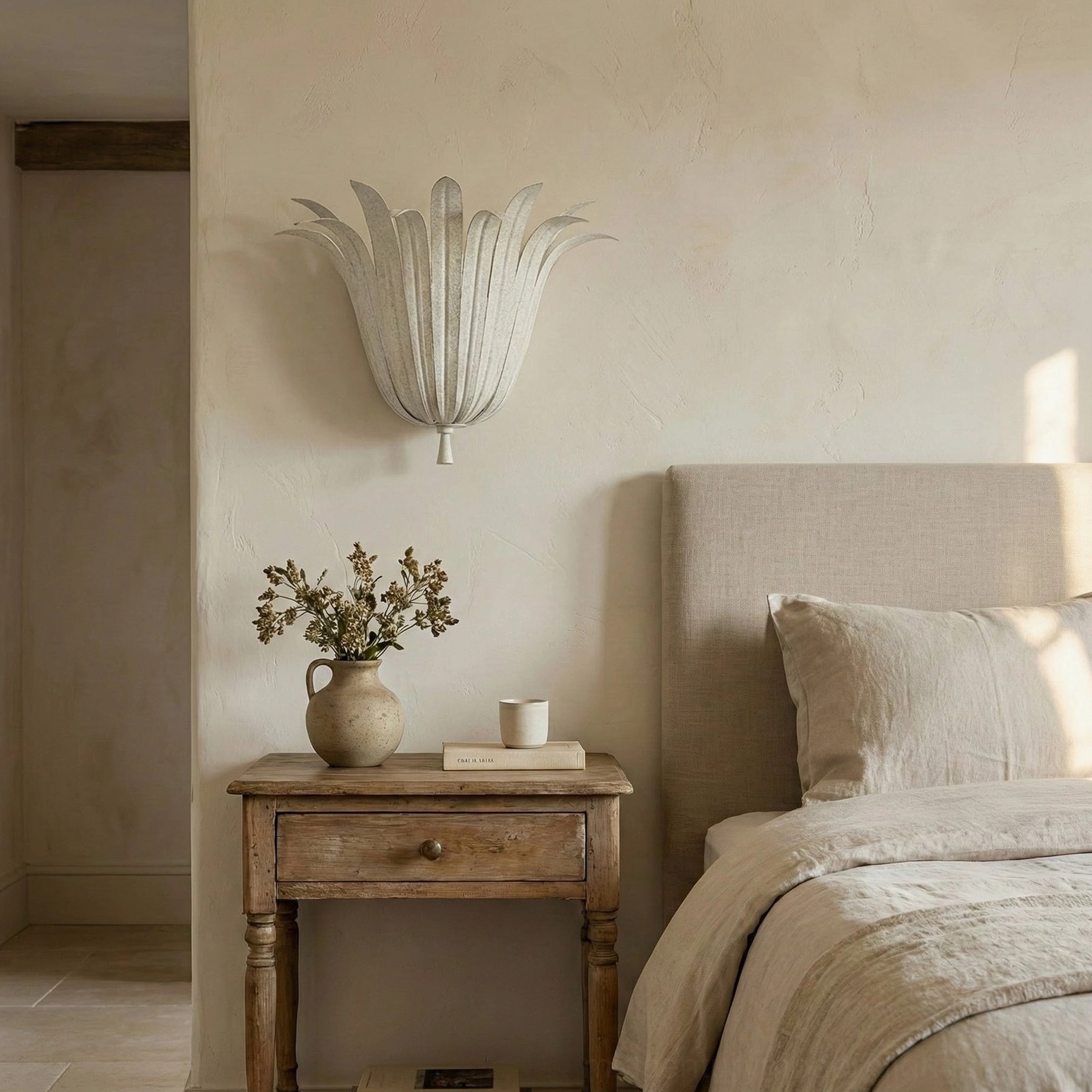 Vicenzio Leaf Wall Sconce in off-white finish installed above wooden nightstand in minimalist neutral bedroom