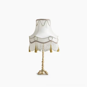 Victorian brass table lamp with white fabric shade and gold-braided trim on pure white background