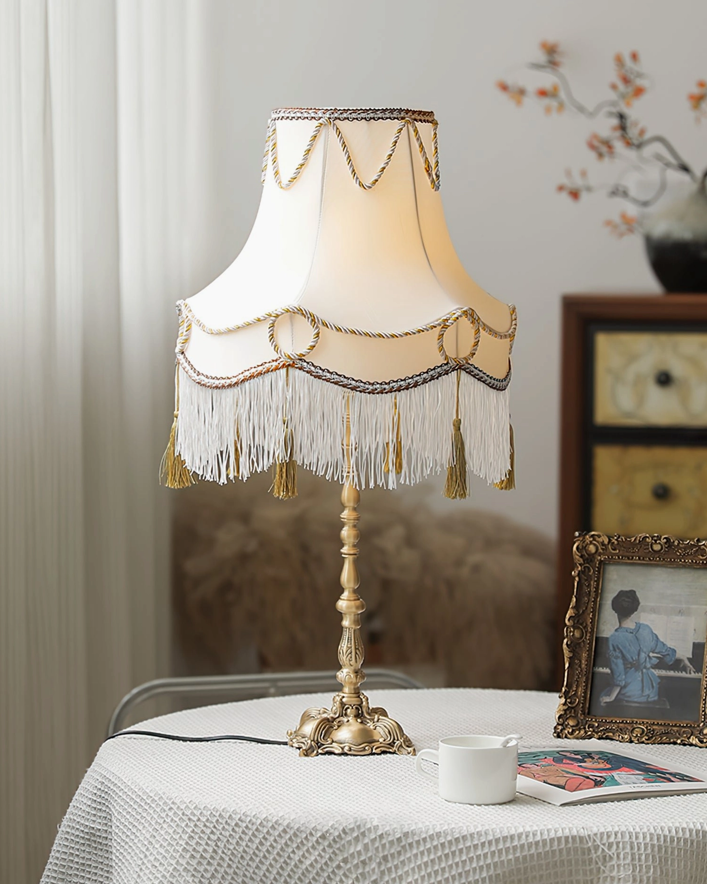 Victorian table lamp with fringed shade and mixed trims displayed with vintage ornaments