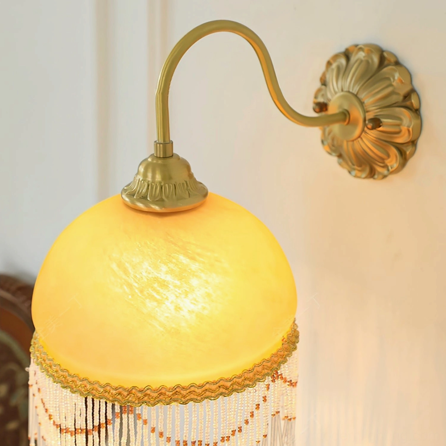 Vili wall lamp hardware close-up showing embossed floral brass wall mount and curved metal arm architectural detail