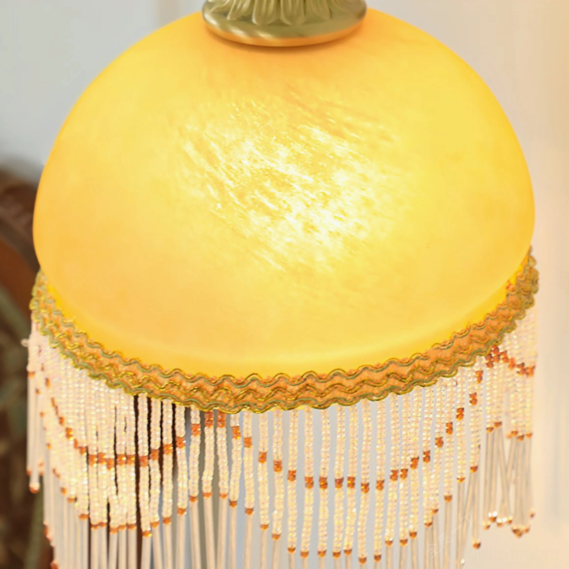 Close-up detail of Vili lamp shade showing marbled frosted glass, gold ruffled trim, and layered beaded fringe decoration