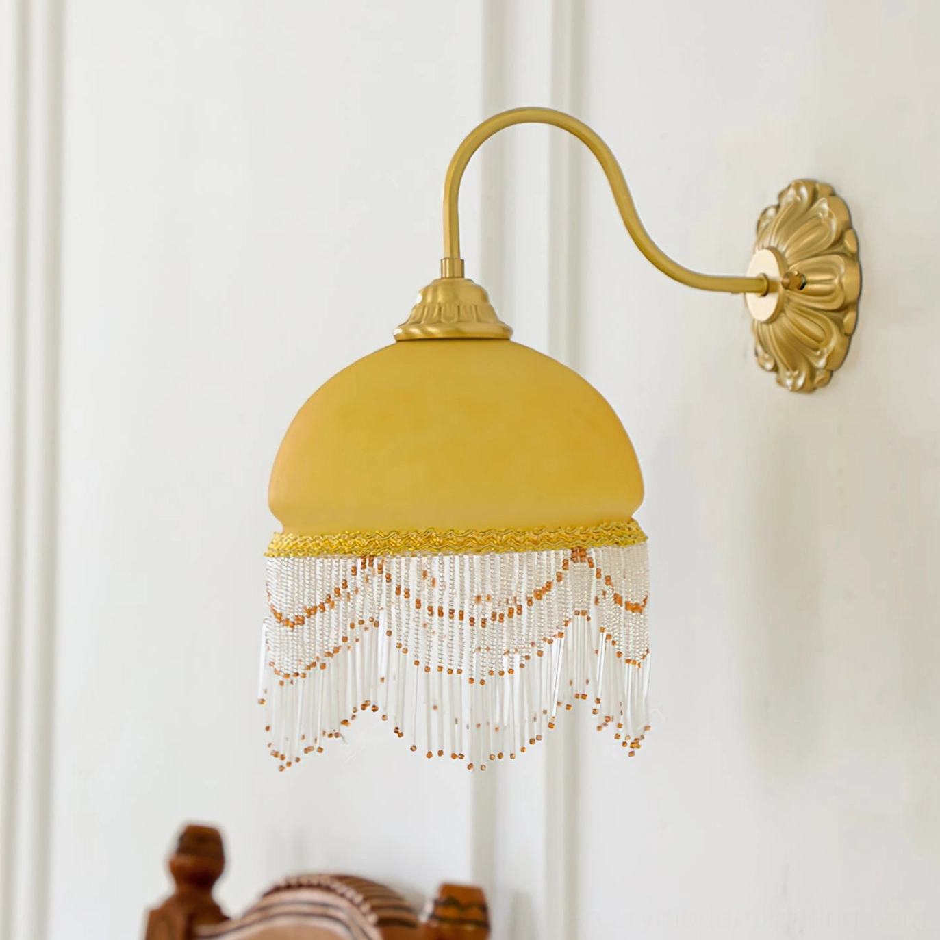 Vili wall lamp front view showing full tassel decoration, gold decorative band and double-layer beaded tassels on light indoor wall