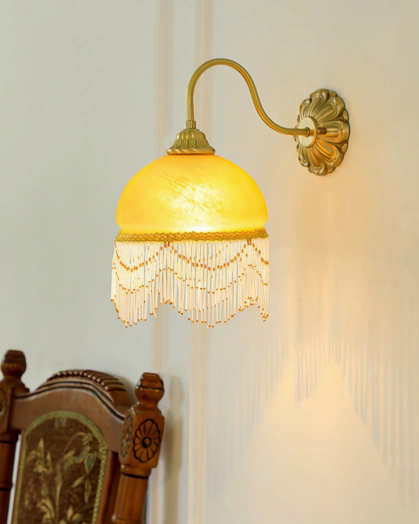 Vili wall lamp illuminated beside vintage dining chair, soft warm ambient light and delicate tassel trim in home interior