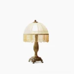 Vintage brass tassel flower table lamp with frosted glass shade and beaded fringe trim, studio front view on white background