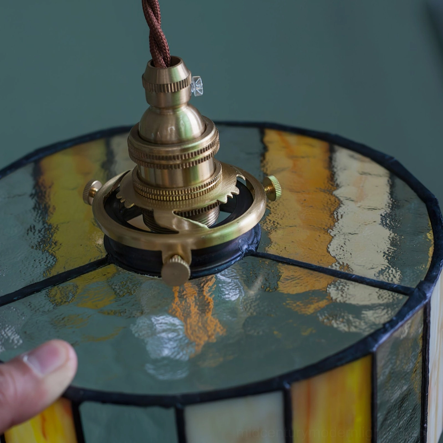 Vintage stained glass pendant lamp with warm diffused lighting, brass fixture, and classic mid-century modern design aesthetic