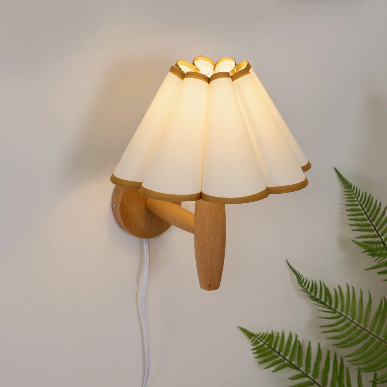 Lit vintage fluted wall lamp with white pleated shade and green foliage, warm ambient glow