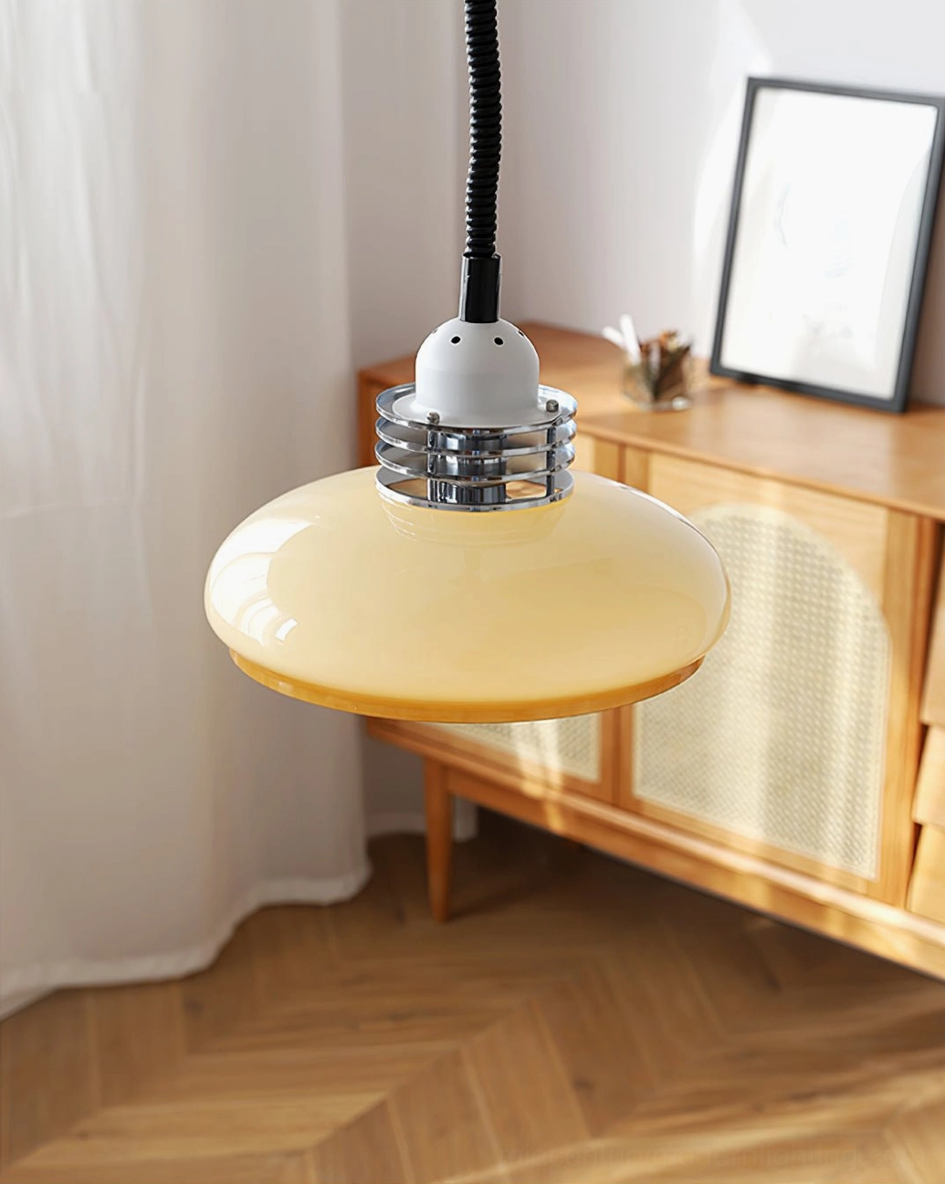 Vintage pendant lamp suspended in cozy living space with wooden cabinet, framed wall art, and warm wood flooring
