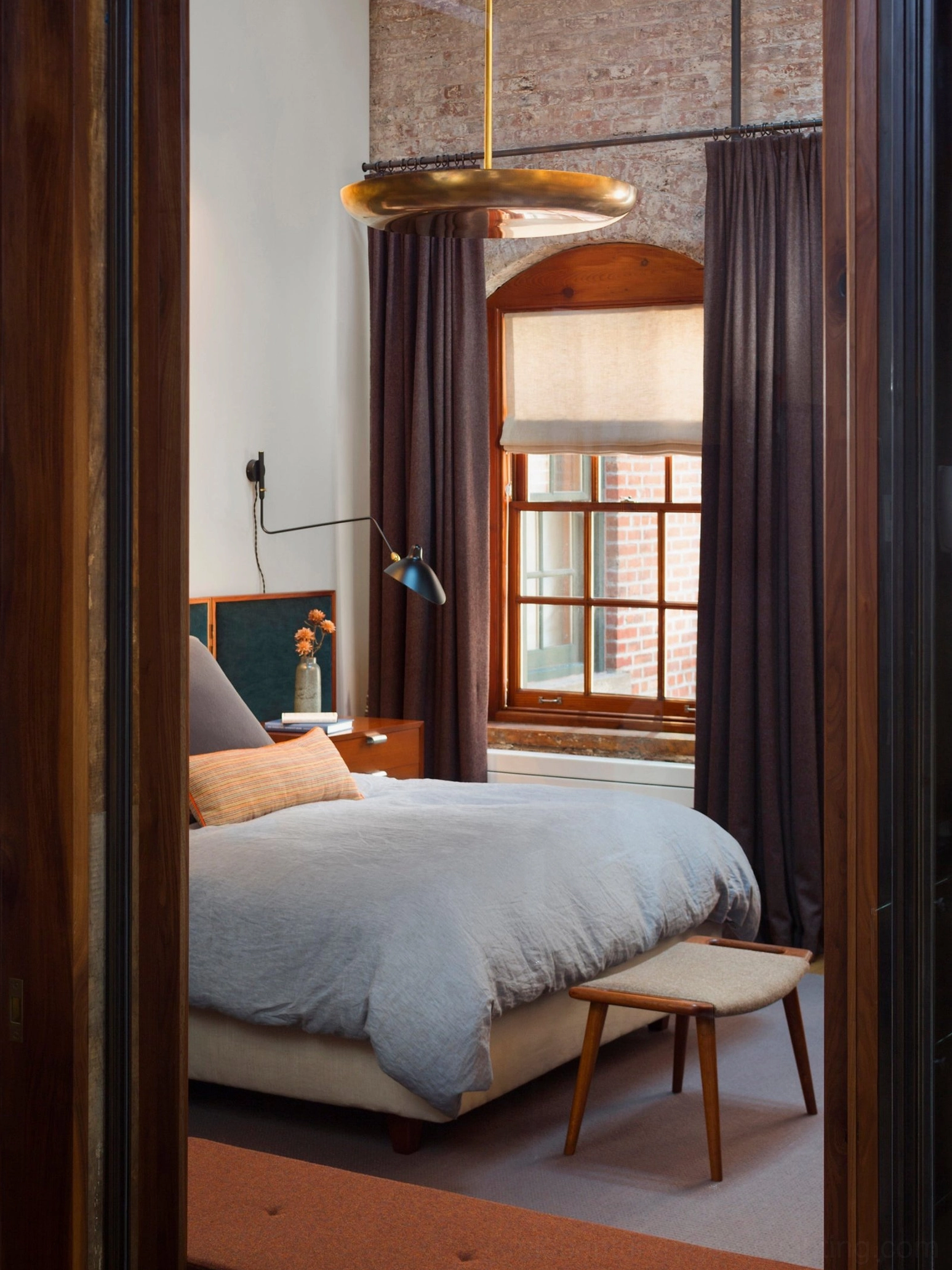 Matte black single-arm wall sconce styled with matching industrial pendant in vintage bedroom aesthetic