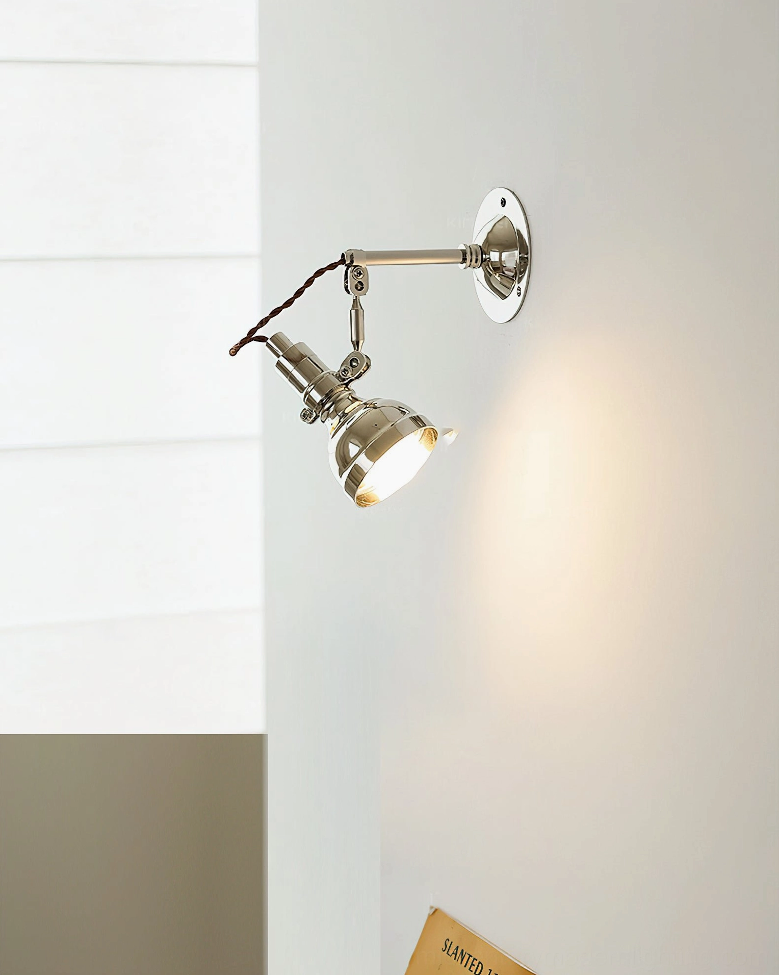 Side oblique view of swing arm wall lamp with exposed twisted wire and warm glowing LED bulb