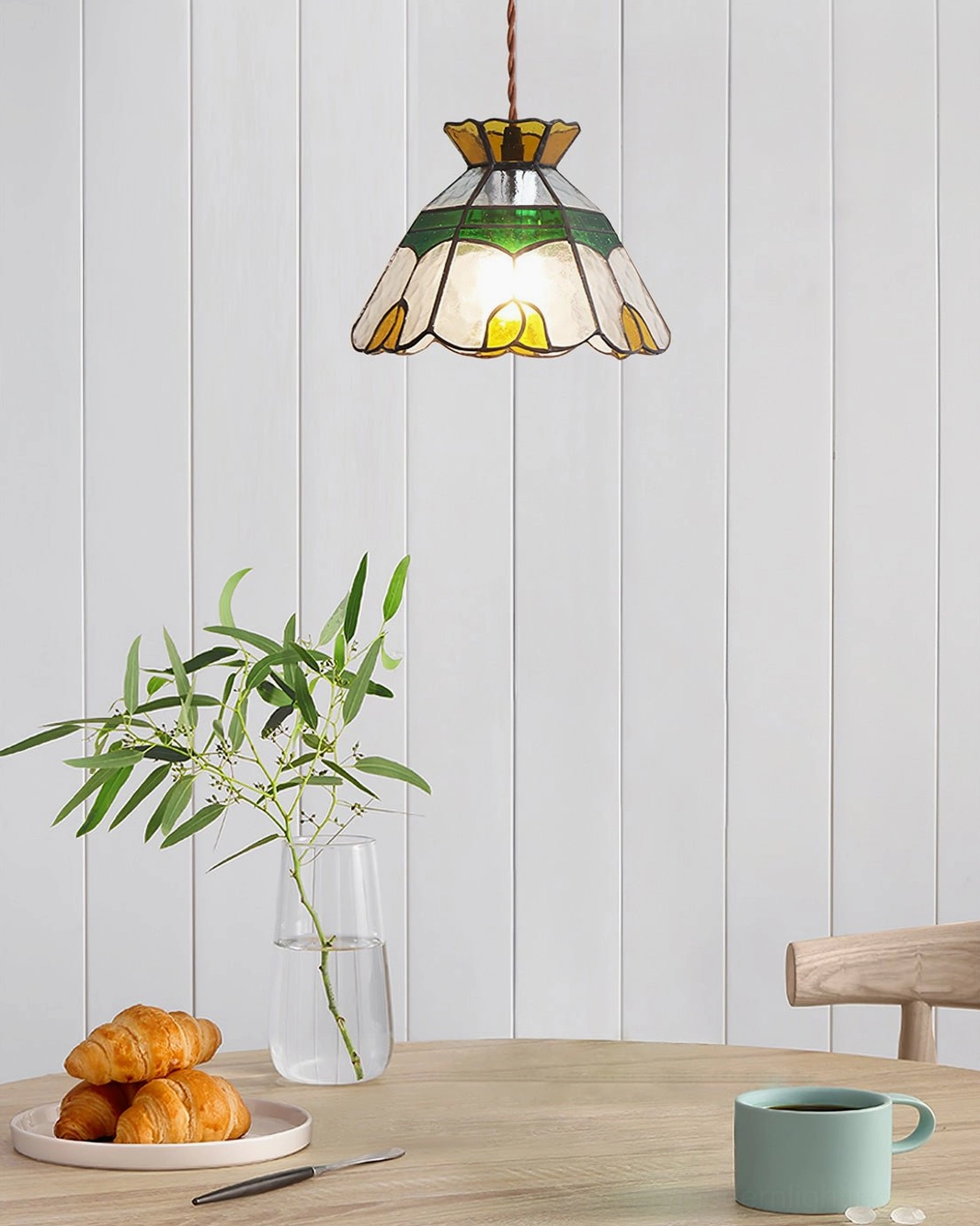 Vitral stained glass pendant lamp hanging above dining table with potted plant and tableware