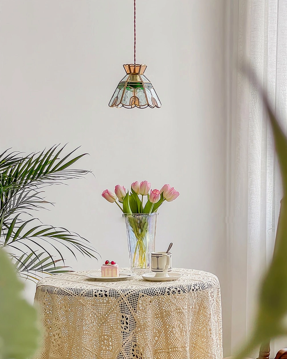 Handcrafted stained glass pendant light in vintage dining corner with lace tablecloth and floral arrangement
