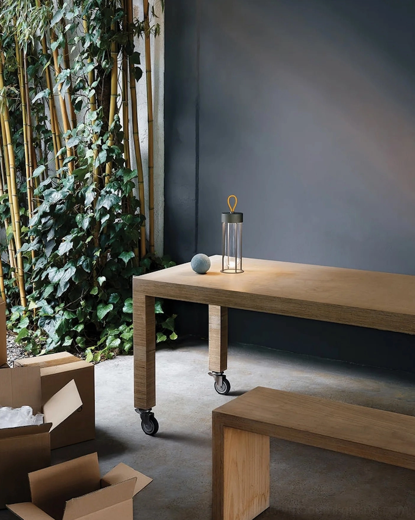 Wireless Vitro table lantern on rolling wooden table with matching stone decor in patio space