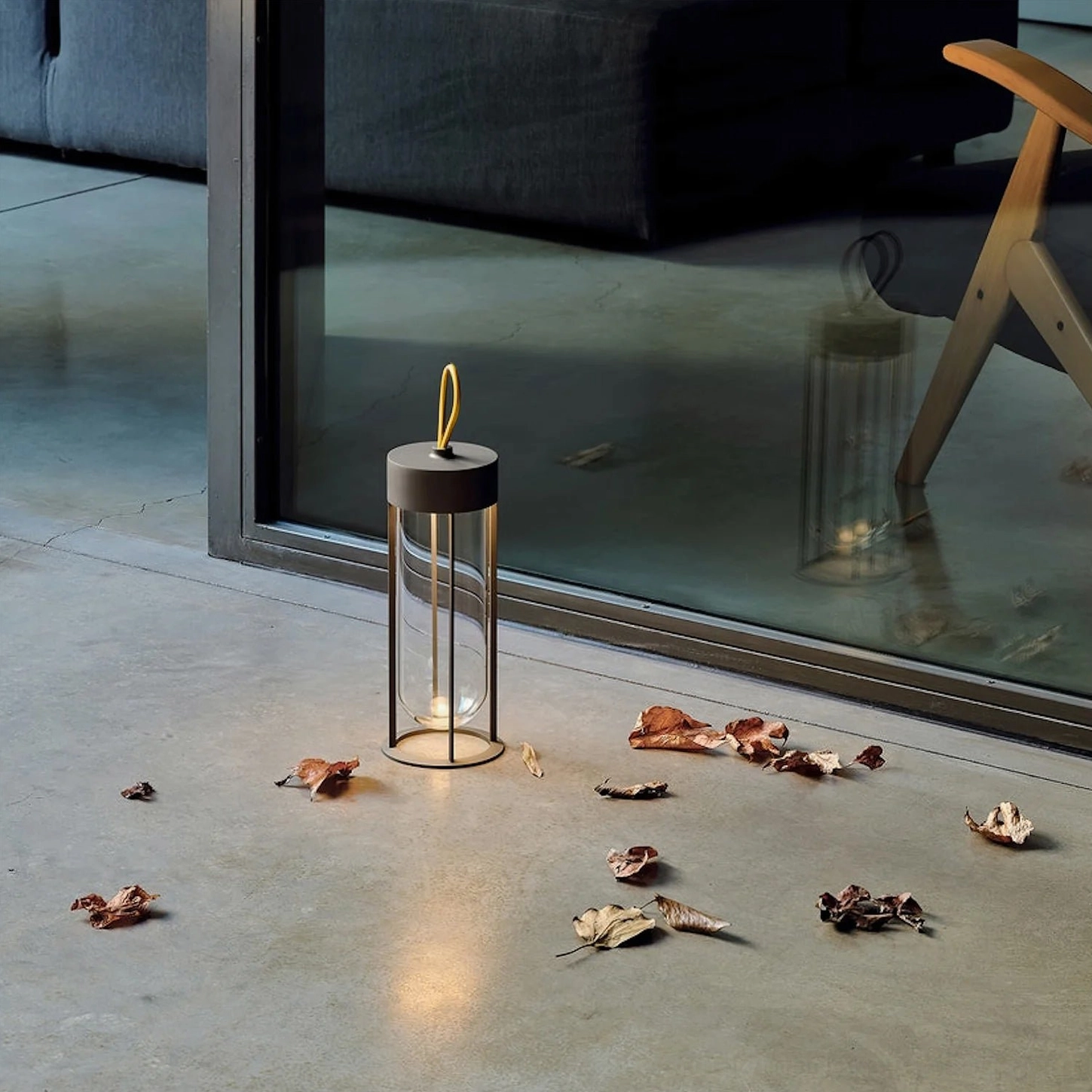 Battery-powered Vitro outdoor patio table lamp with warm light near concrete and fallen leaves