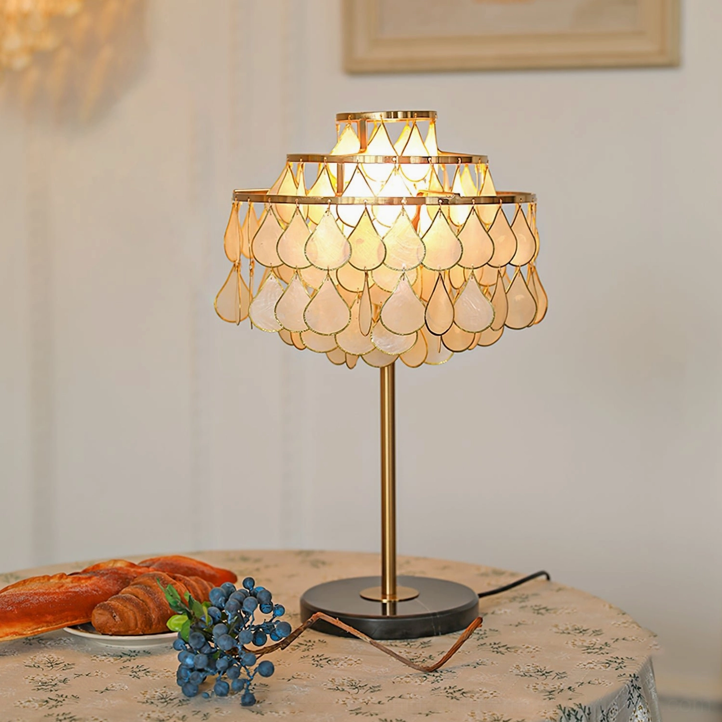 Vivant Shell Table Lamp on dining table with floral tablecloth and pastries in cozy vintage home setting