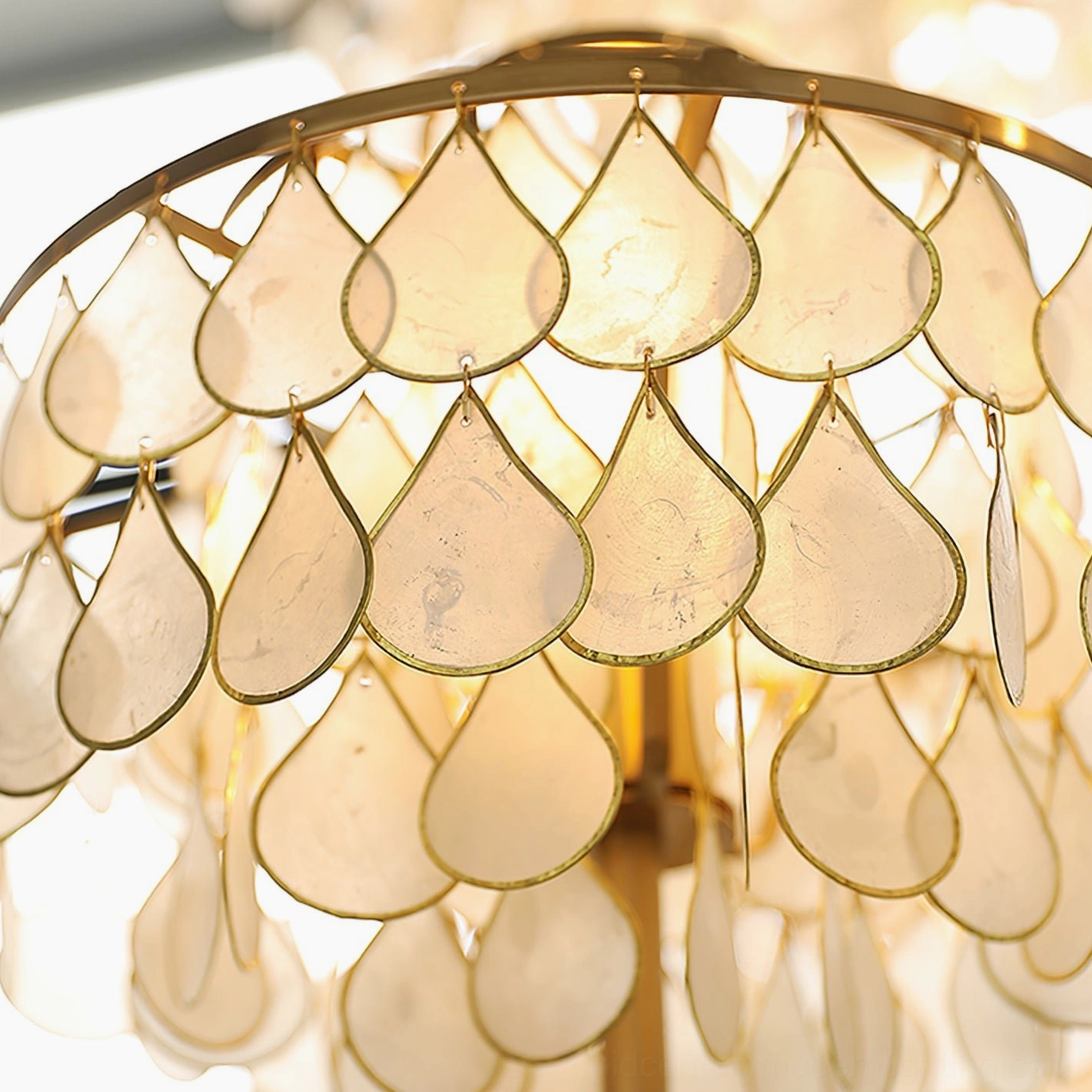 Close-up detail of Vivant Shell Table Lamp shade tear-shaped shells gold metal framing and warm backlight