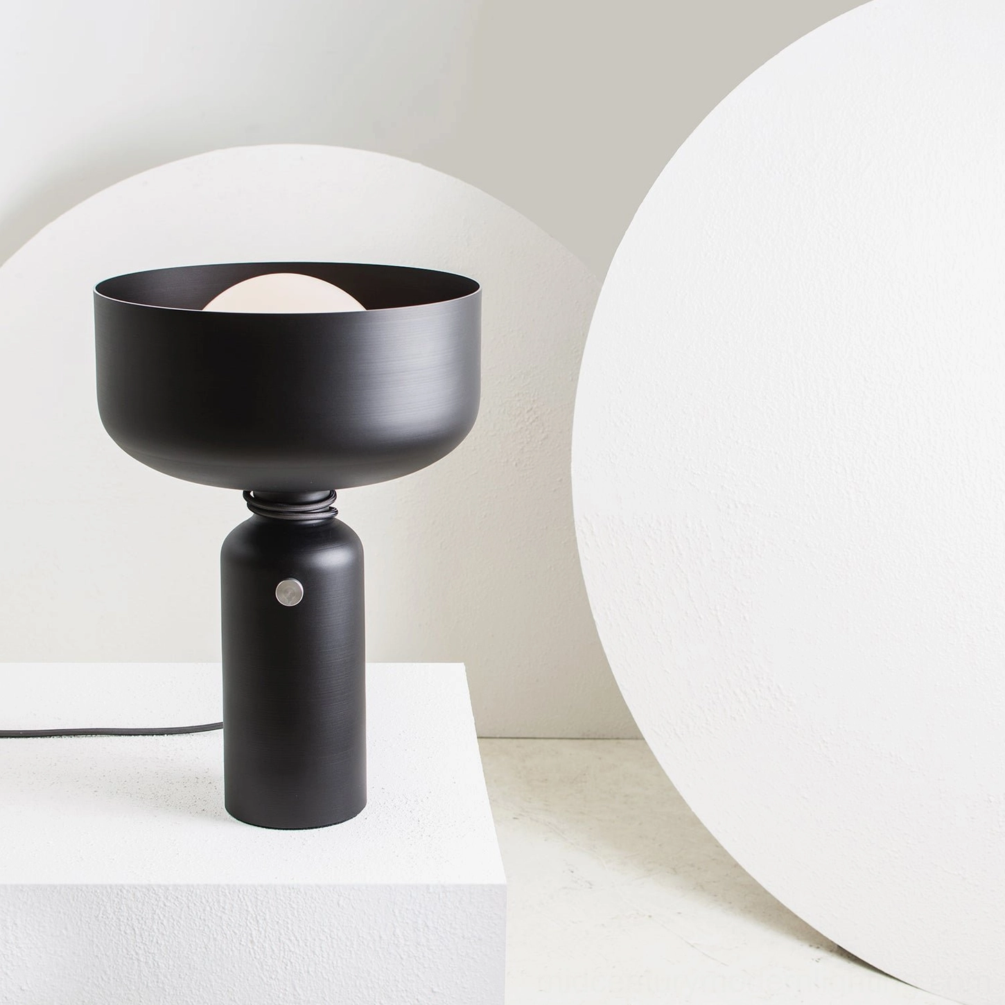 Vol black table lamp on display pedestal with artistic studio backdrop