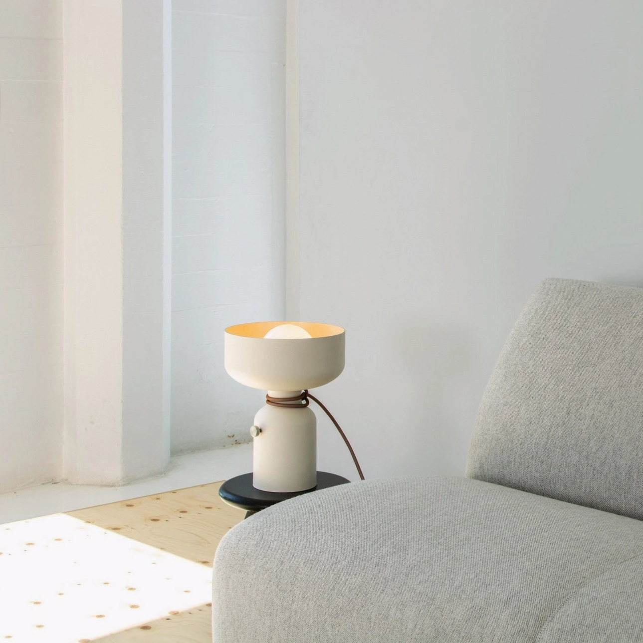 Vol off-white table lamp lit with warm ambient light in modern living room with grey sofa