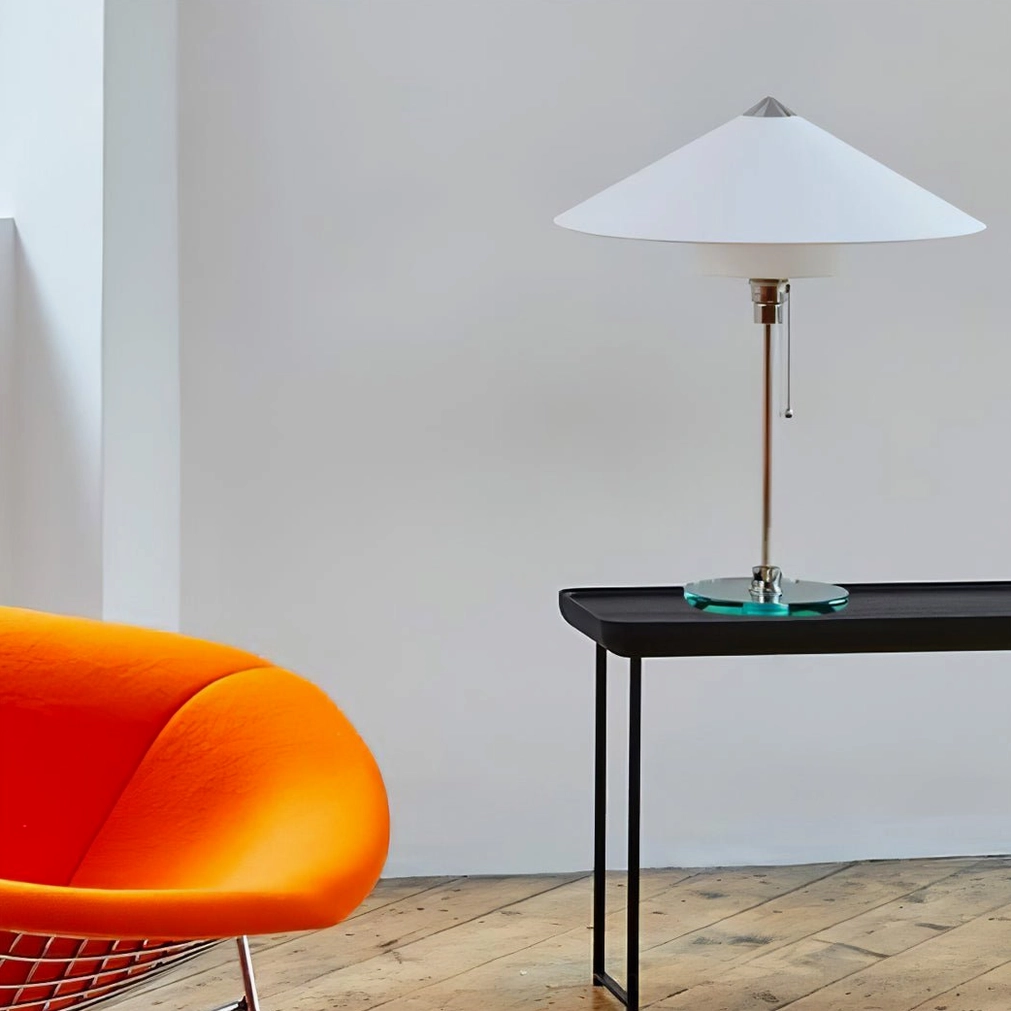 Wagenfeld design table lamp on black console table minimalist living room with orange accent chair