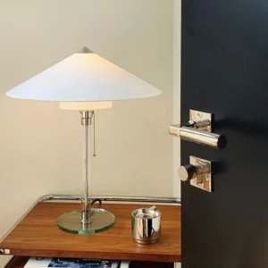 Wagenfeld Bauhaus table lamp three-quarter angle showing pull chain switch and polished chrome hardware in home interior setting