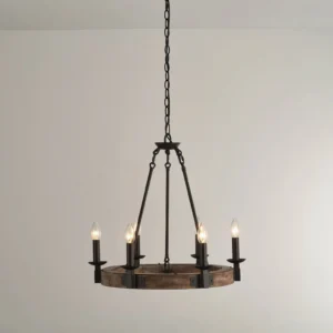 Industrial rustic wagon wheel chandelier mounted from ceiling chain, four lit candle bulbs glowing warm amber light against neutral wall