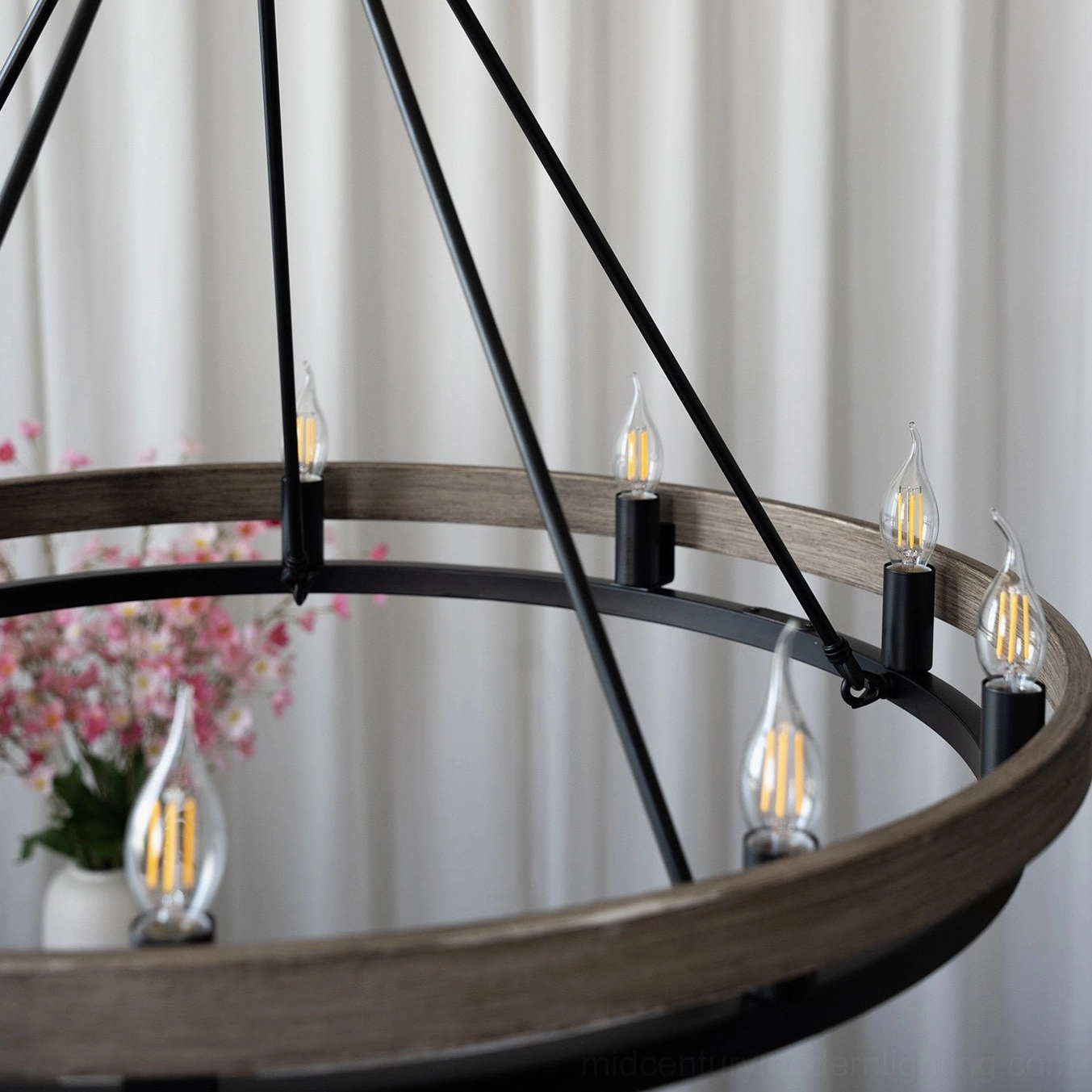 Side close-up of wagon wheel chandelier ring structure showing walnut wood and black metal combination with exposed candle LED bulbs