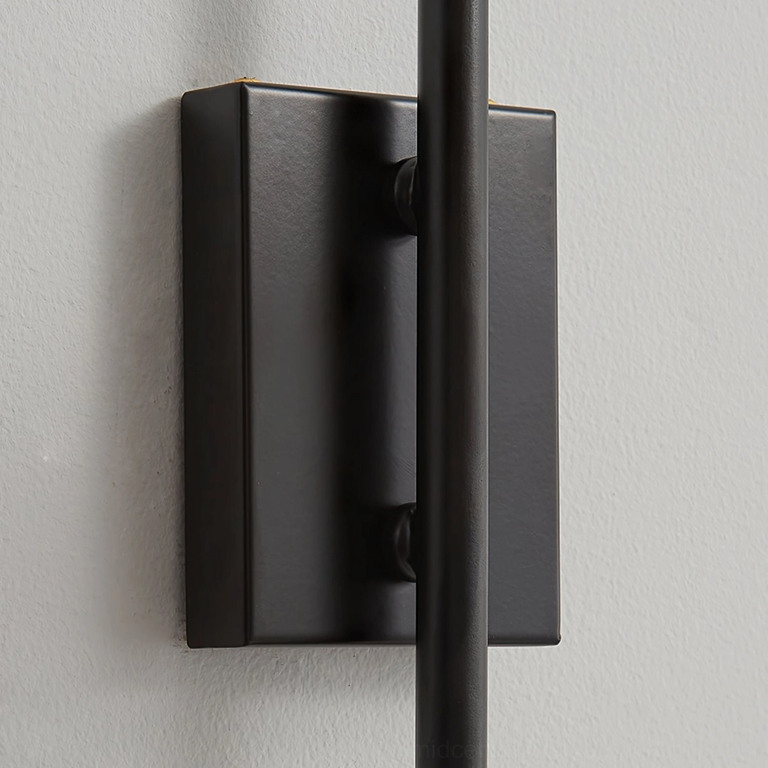 Riankh wall lamp mounting bracket and base detail showing matte black metal finish, close-up overhead view
