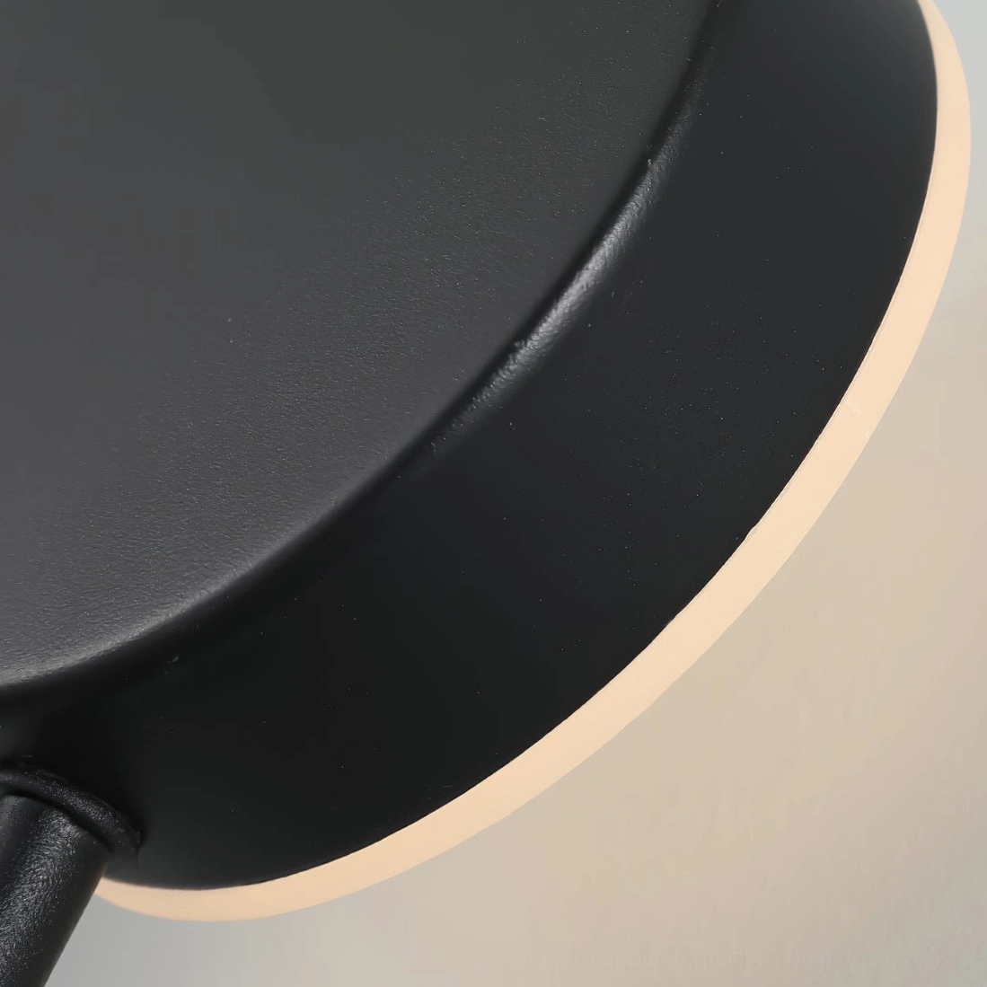 Close-up macro view of matte black wall lamp hardware and glowing LED edge trim detail