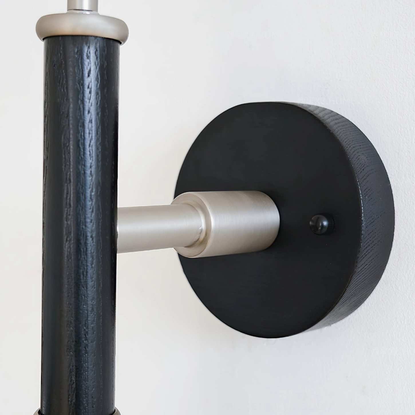 Close-up detail of wall sconce mounting hardware, brushed silver bracket and black wooden pole
