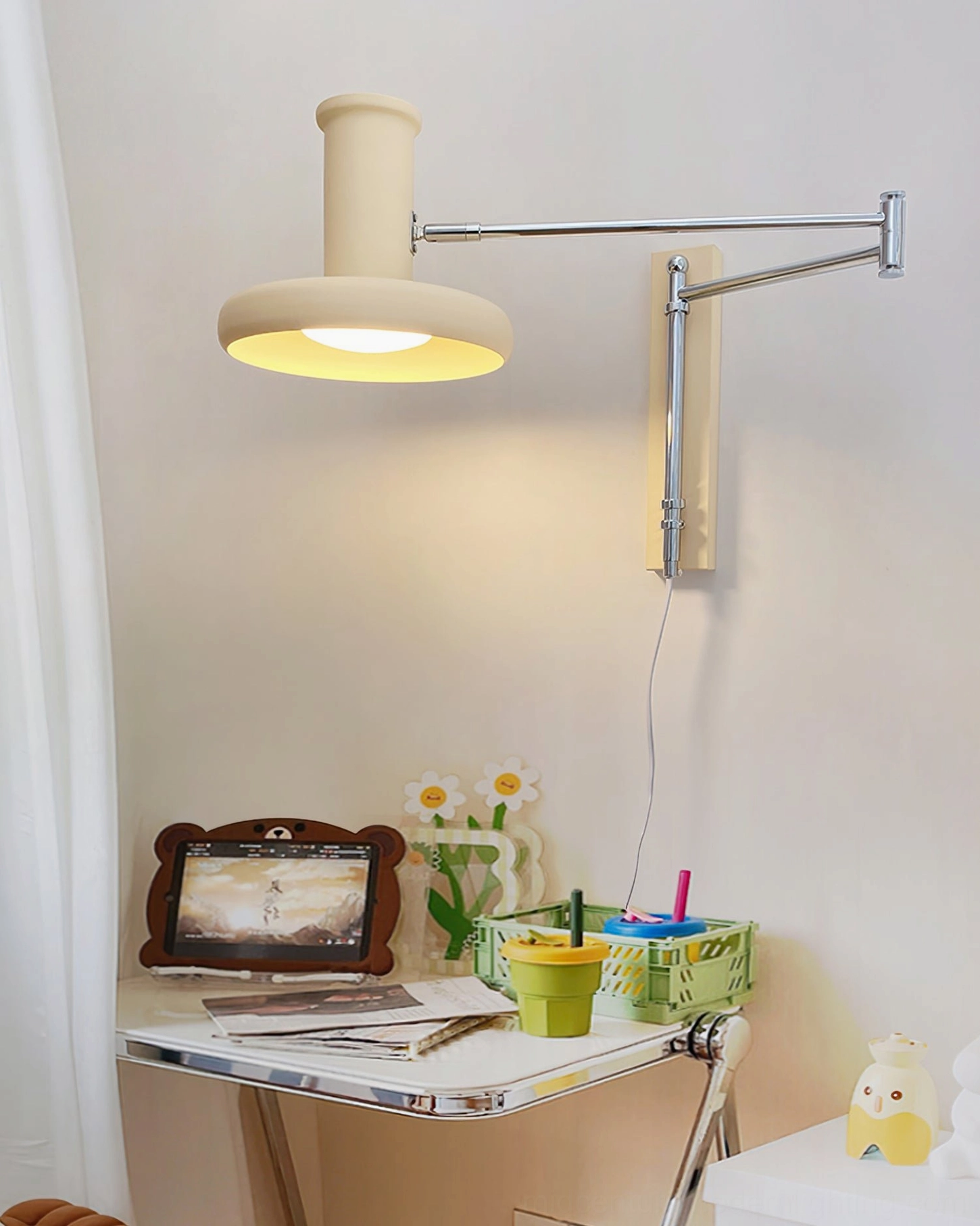 Modern swing arm wall sconce in home workspace over cozy study desk with warm task reading lighting and decorative accents