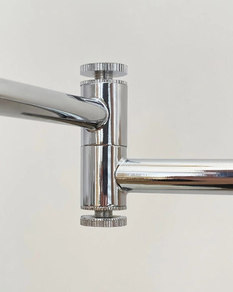 Detailed macro view of adjustable swing arm joint with knurled chrome locking knobs from top-down angle