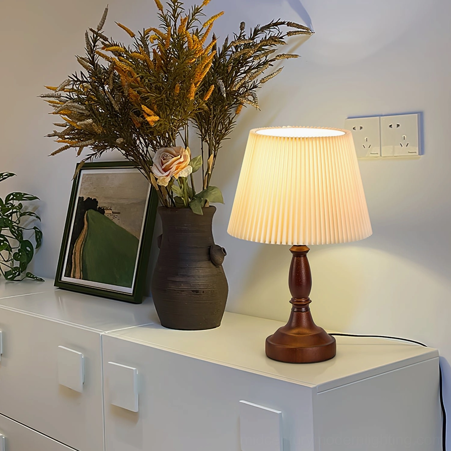 Mid-century table lamp on white entryway cabinet with dried flowers and framed art in neutral home style