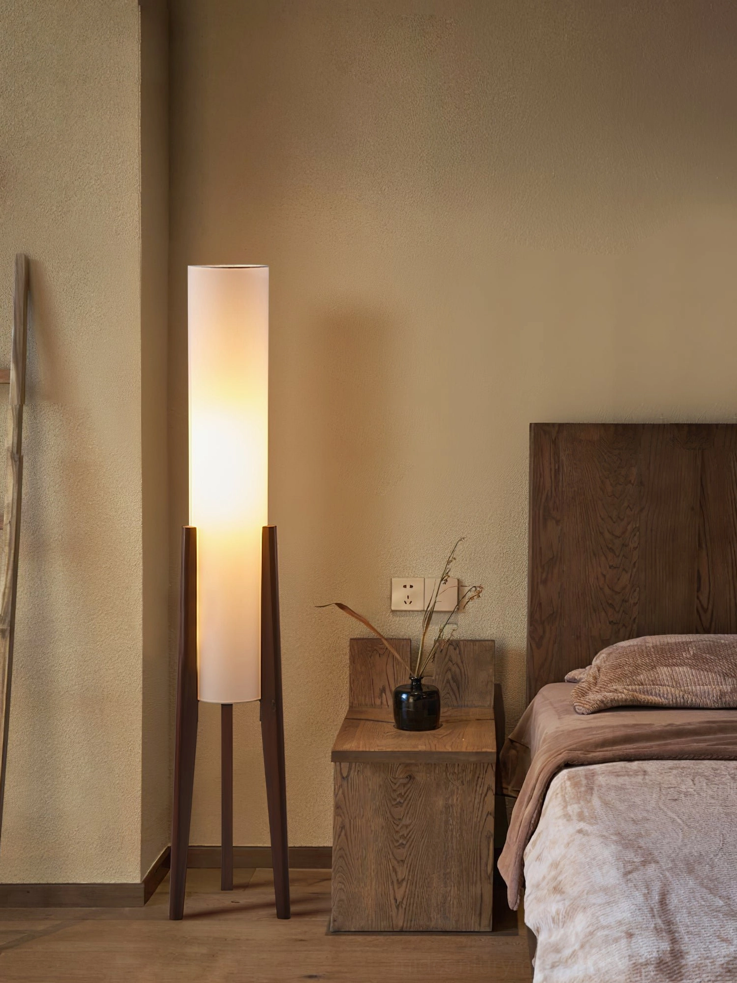 Compact walnut tripod floor lamp in master bedroom providing warm ambient lighting beside nightstand