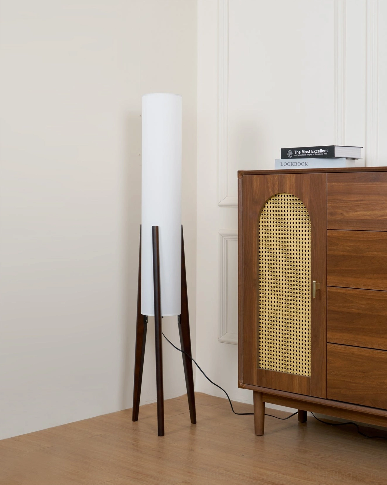 Mid-century walnut tripod floor lamp illuminated in warm light showing fabric shade glow