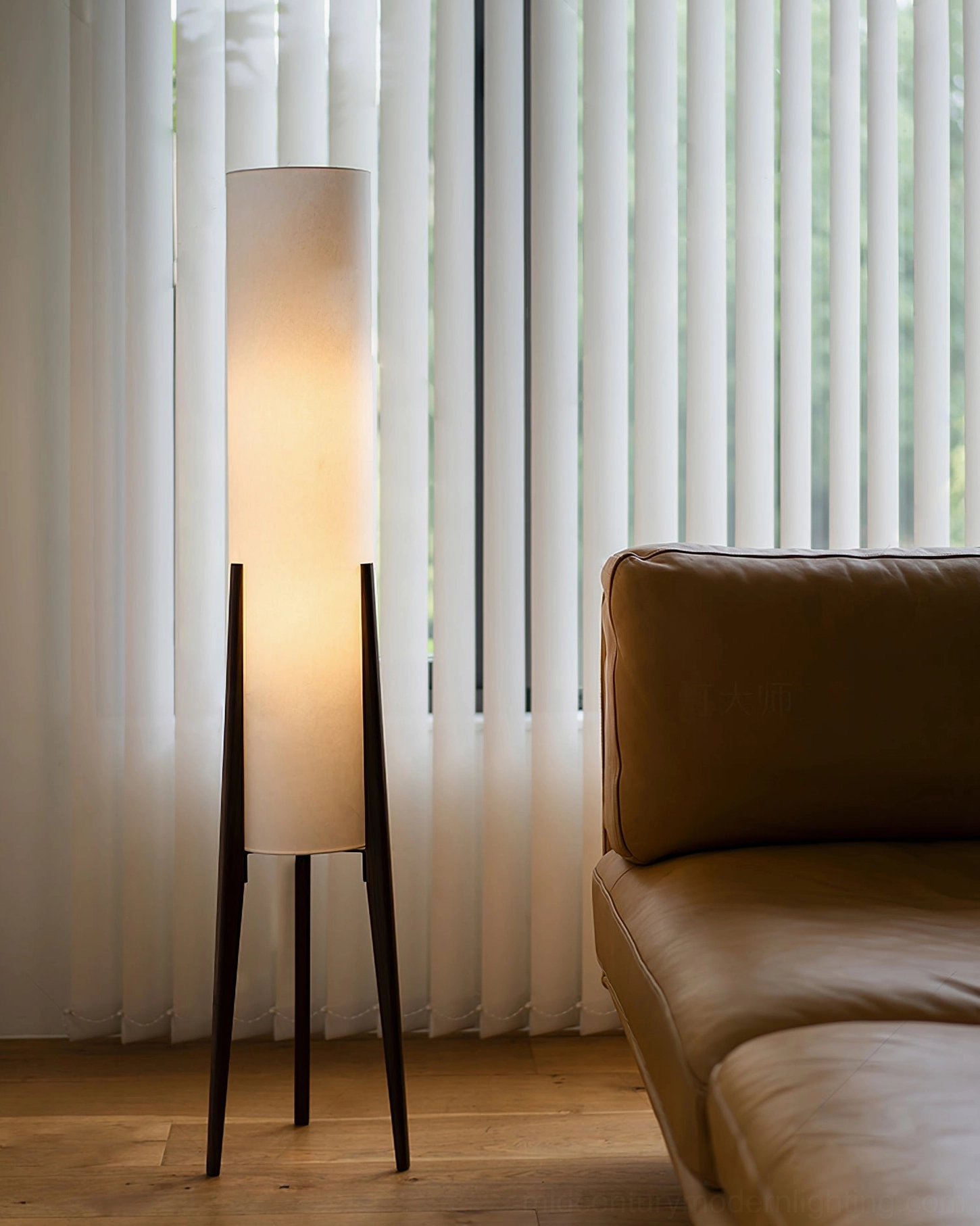 Dark walnut wood tripod lamp with white fabric shade in modern living room beside leather sofa
