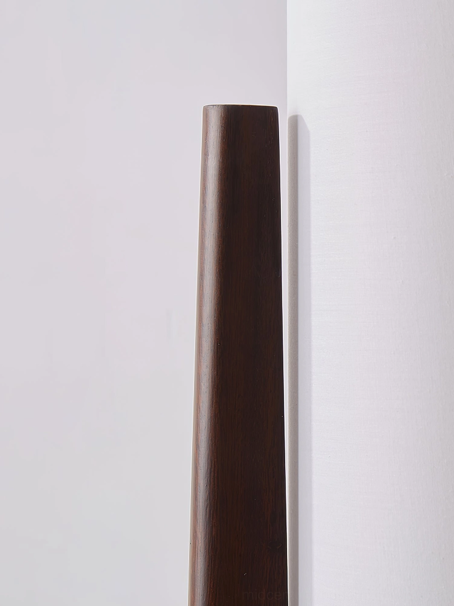 Close-up detail of smooth dark walnut wood grain on tapered tripod floor lamp leg